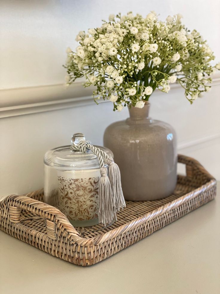 a wicker tray with a jar and flowers on it