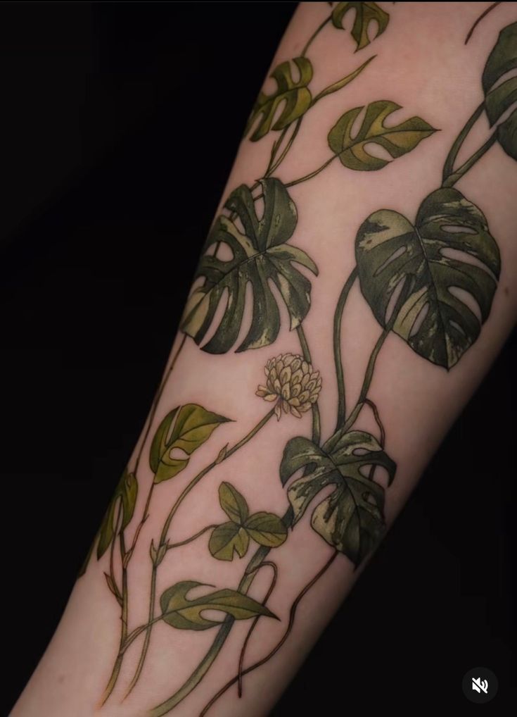 a close up of a person's arm with leaves and flowers on it