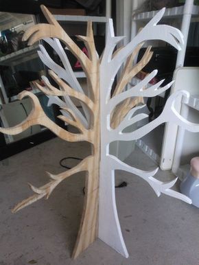 a white tree is standing on the floor in front of a mirror and another piece of wood