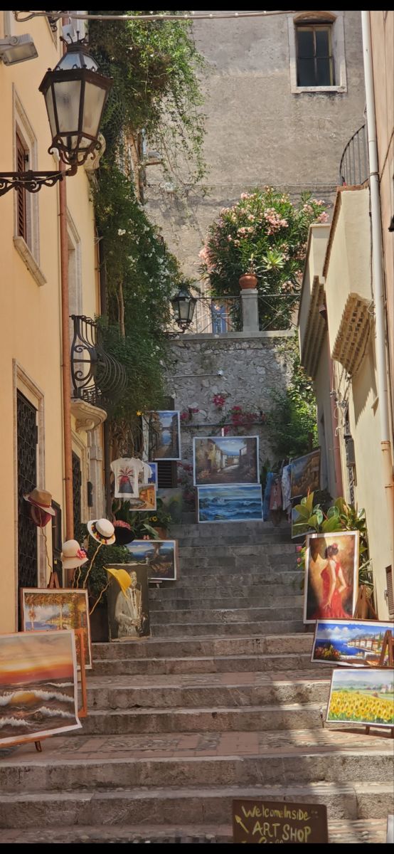 an alleyway with stairs and paintings on display