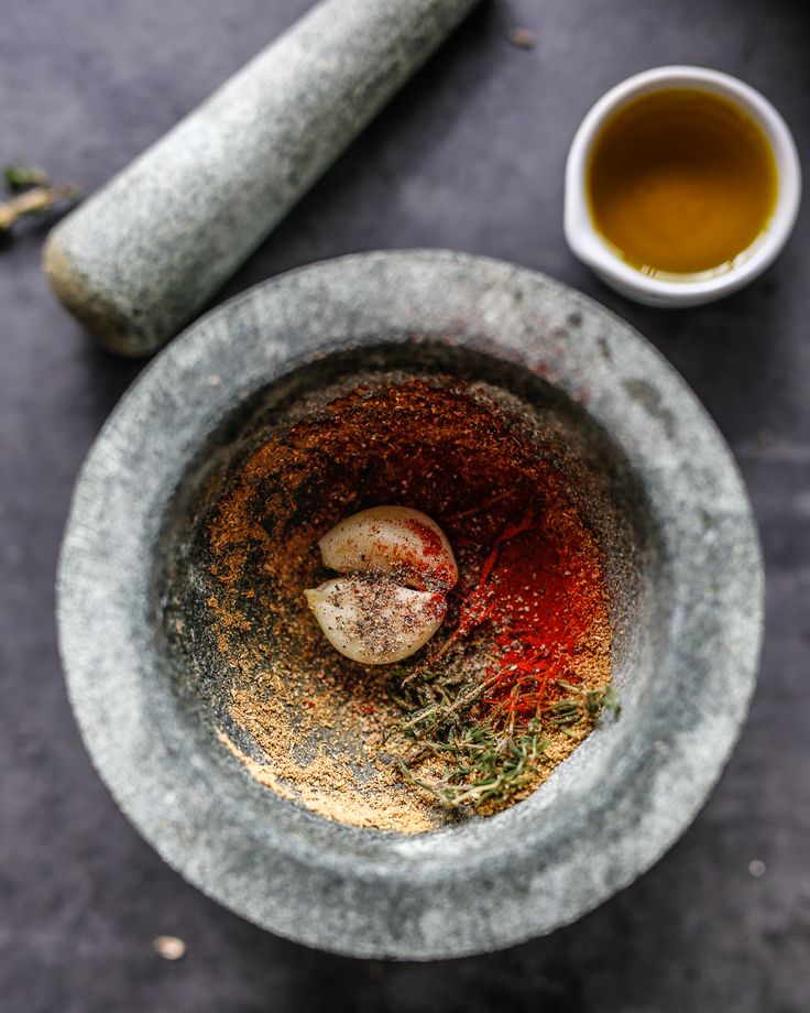 a mortar bowl filled with spices next to a cup of tea