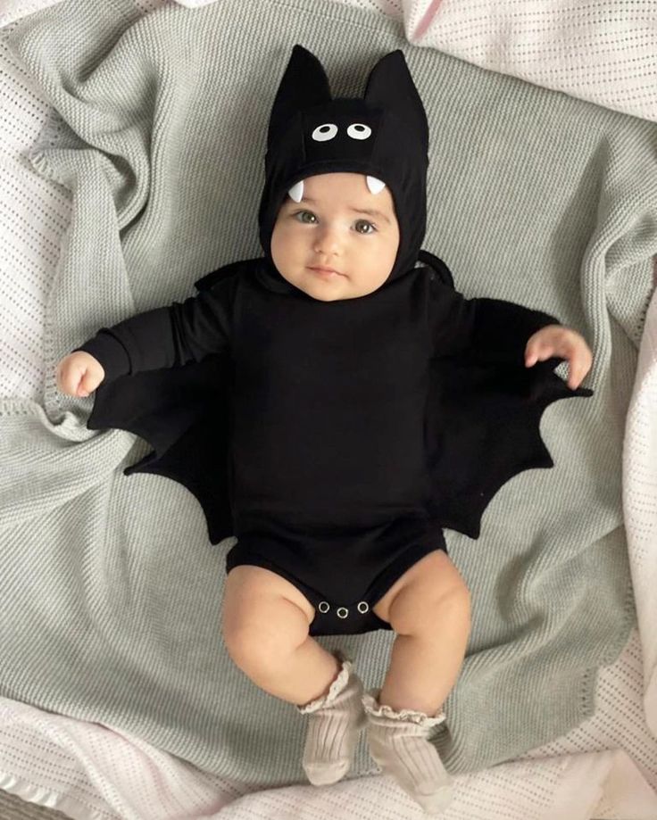 a baby wearing a batman costume on top of a bed