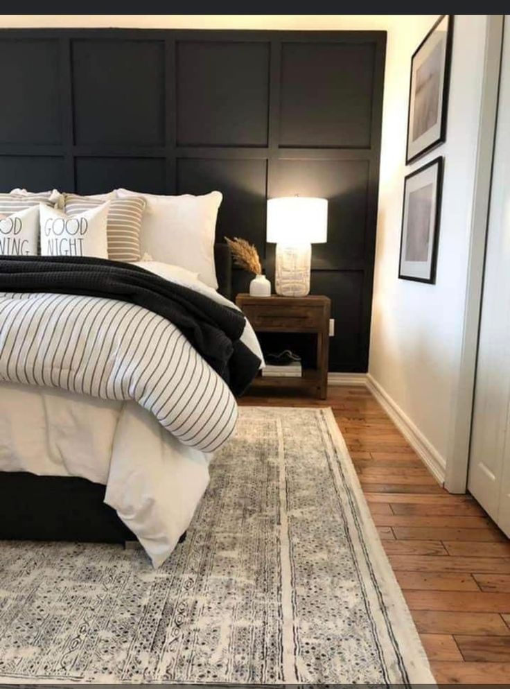 a bedroom with black headboard, white bedding and rugs on the floor