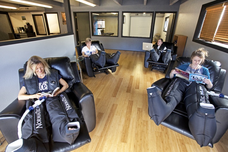 two women sitting in recliners with bags on their laps and one woman reading