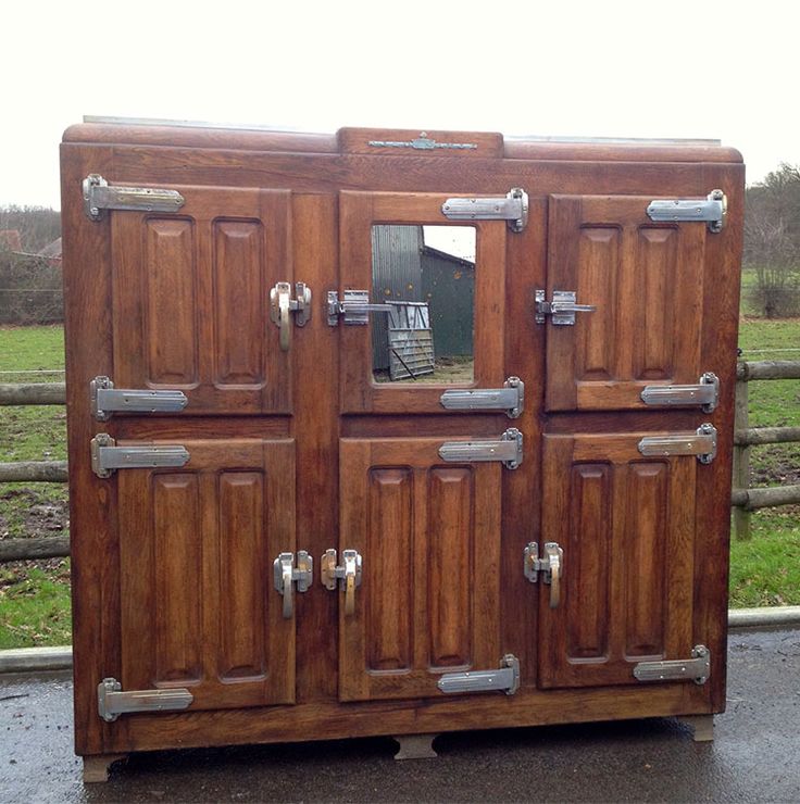 an old wooden cabinet with metal handles and knobs on the doors is sitting in front of a fence