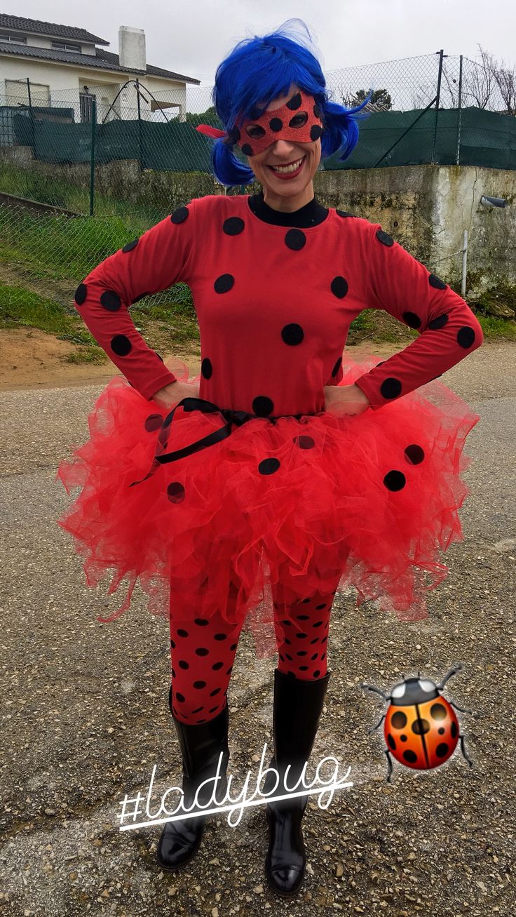 a ladybug costume with blue hair and black polka dots on her face is standing in the street