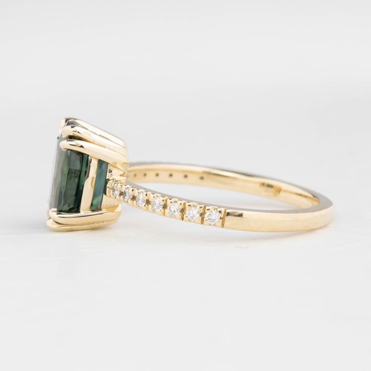 a gold ring with an emerald and diamond band on the side, in front of a white background