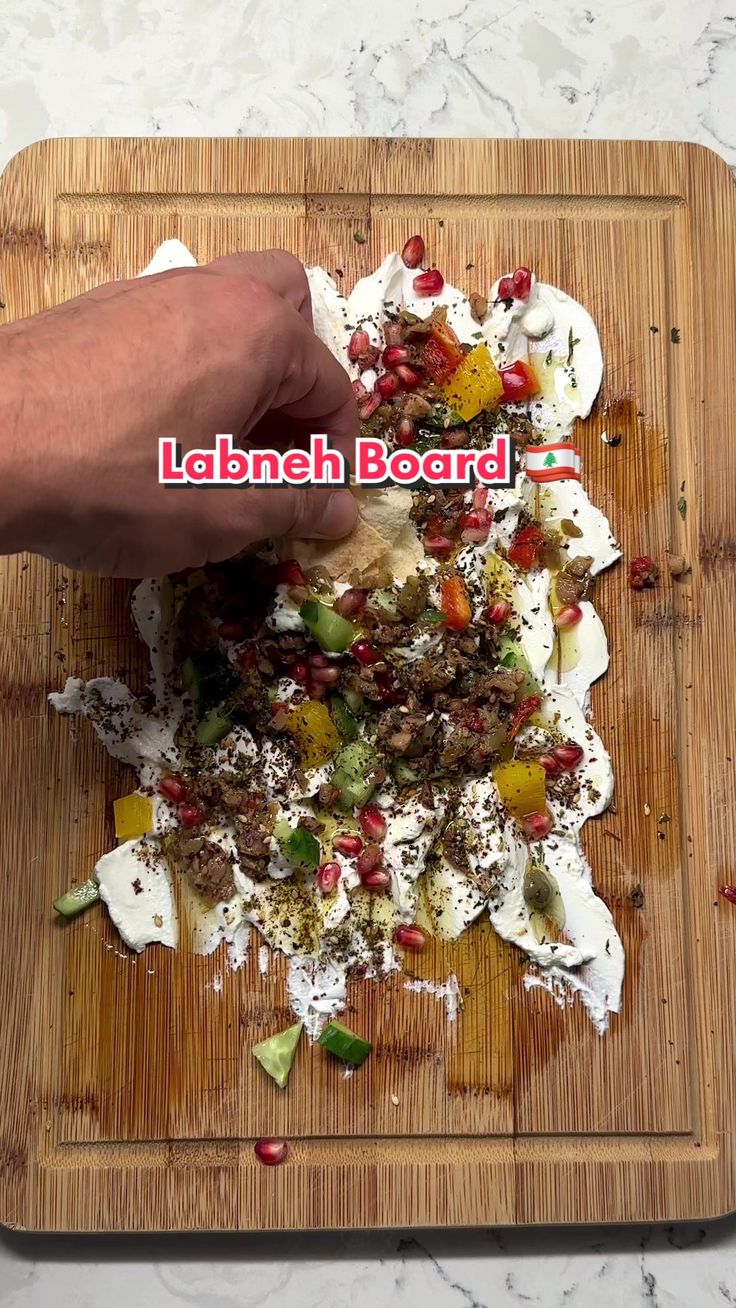 someone is cutting up some food on a wooden board with the words labneh board above it