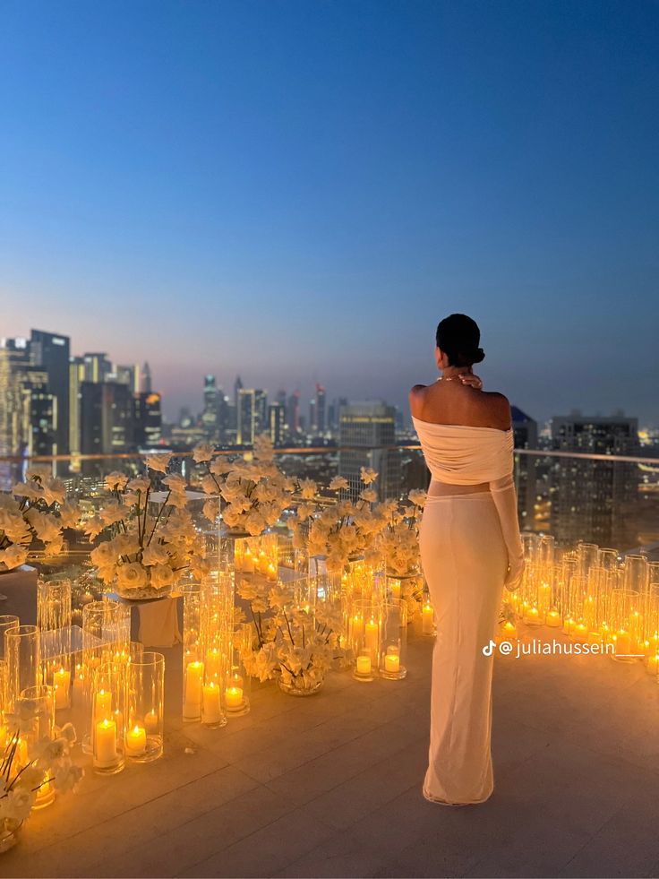 a woman standing on top of a roof next to tall glass vases filled with flowers