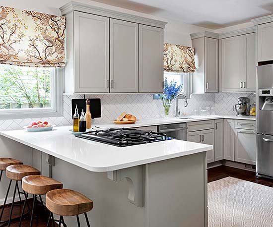 a kitchen with white counter tops and wooden stools in front of the stove top