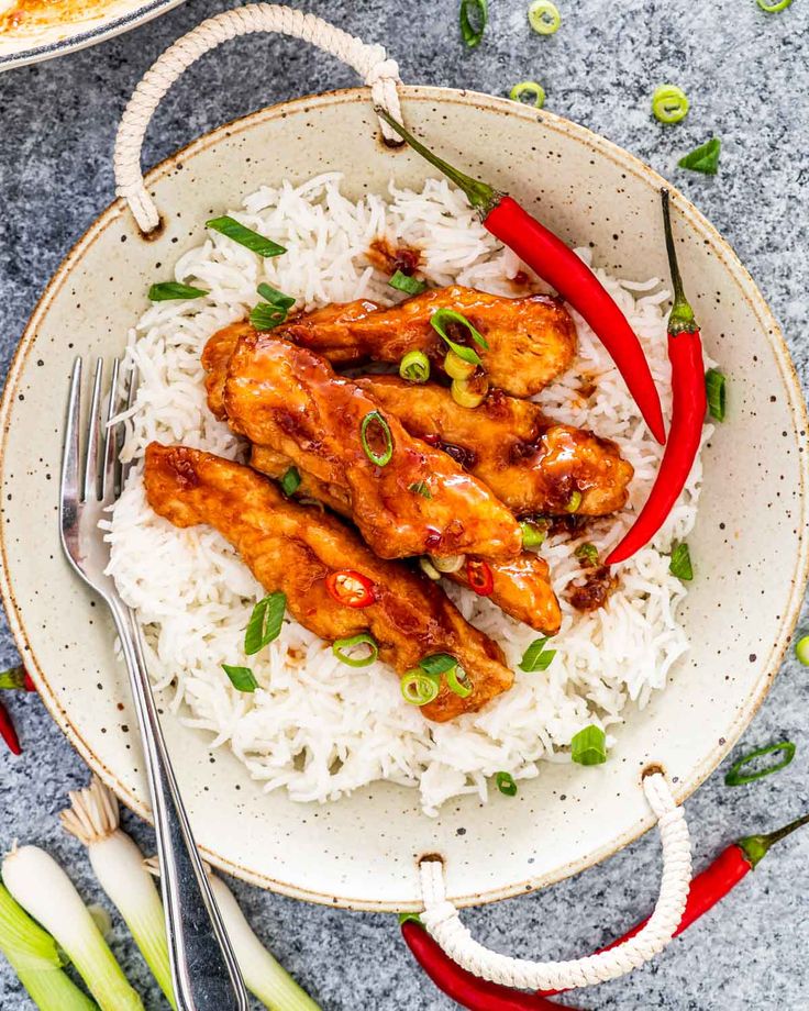 chicken wings and rice on a plate with red peppers, green onions and scallions