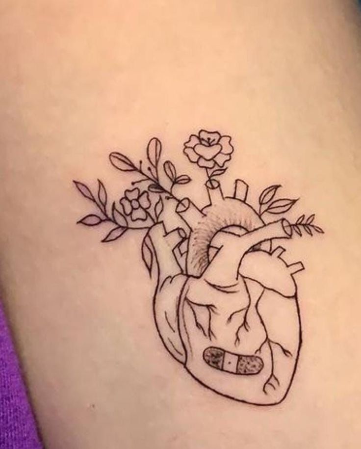 a small heart tattoo with flowers on the inside of it's side ribcage