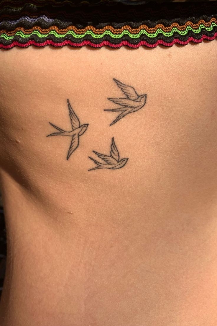 a woman's back with three birds on her side tattooing the lower part of her stomach