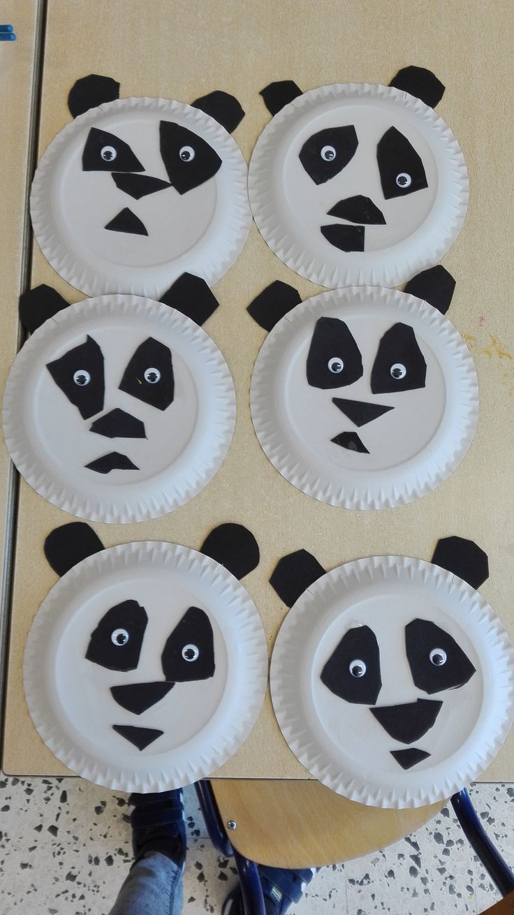 paper plates with panda faces on them are sitting on the floor next to a person's feet