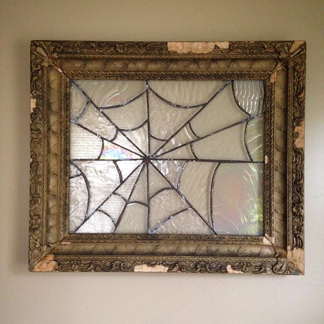 a spider web stained glass window hanging on the wall