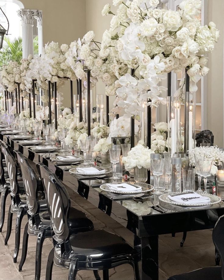 a long table with black chairs and white flowers