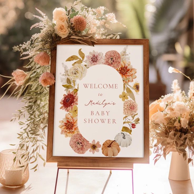 a welcome sign sitting on top of a table next to vases with flowers in them