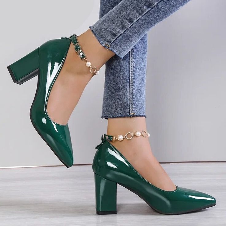 a woman wearing green high heels with pearls on the ankle and her legs in jeans