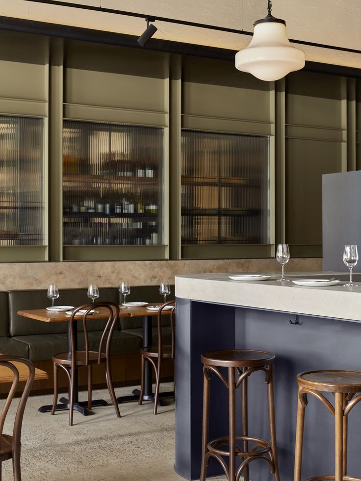 an empty restaurant with bar stools and wine glasses sitting on the counter top in front of it