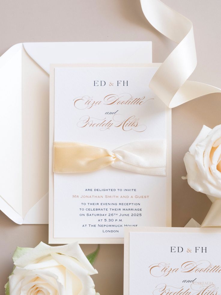 the wedding stationery is laid out on top of each other, with flowers and ribbons