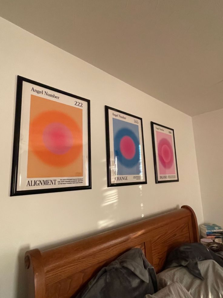 three framed art pieces hang on the wall above a bed