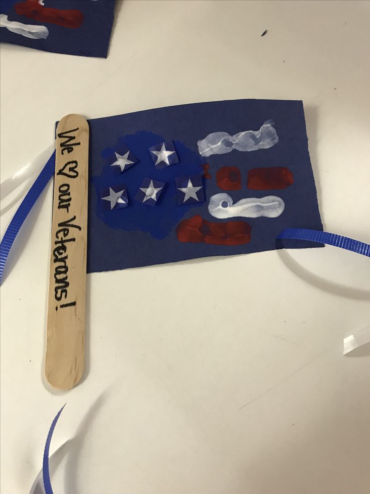 an american flag made out of construction paper with a wooden stick attached to the back