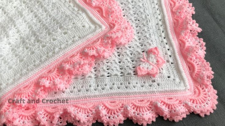 a crocheted blanket with pink and white trimmings on top of it