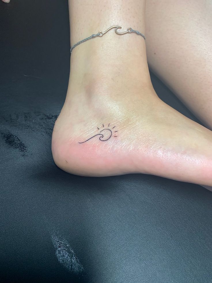 a woman's foot with a small sun tattoo on the side of her leg