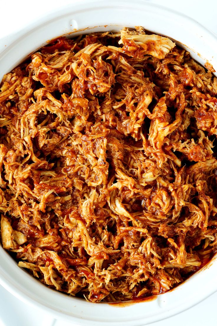 a white bowl filled with shredded meat on top of a table