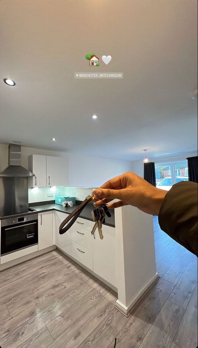 a person is holding keys in their hand while standing in the middle of a kitchen