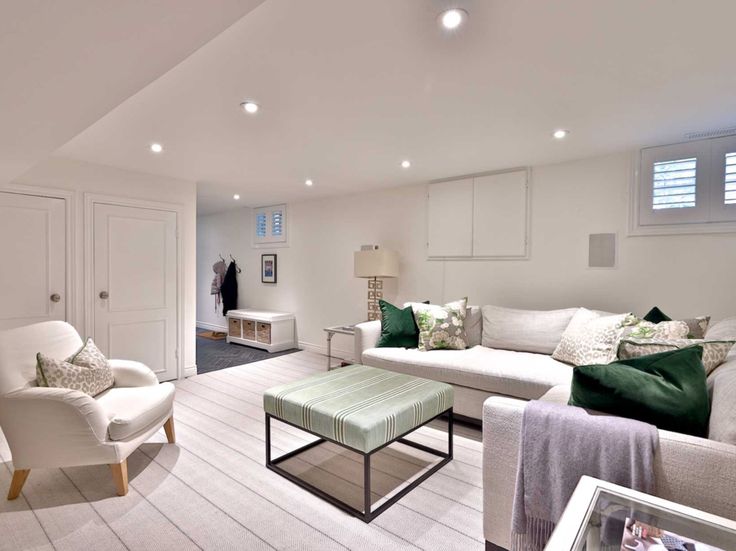 a living room filled with white furniture and green pillows