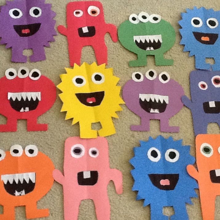 some paper cut outs with different colored monsters on them and one has eyes that are smiling