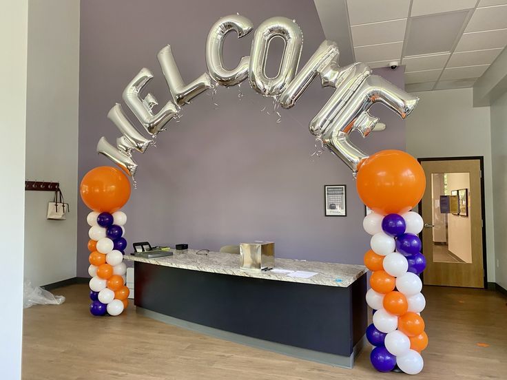 an entrance to a reception hall decorated with balloons and the word welcome spelled in large letters