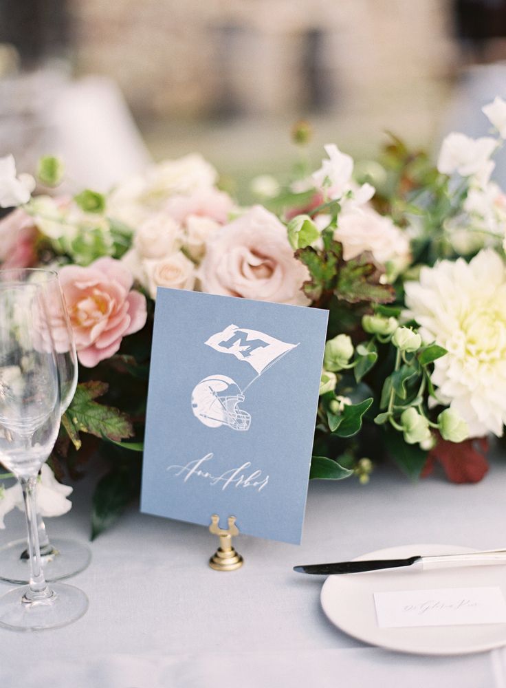 the table is set with white and pink flowers in vases, silverware, and menu cards