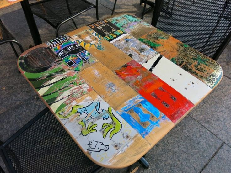 a skateboard sitting on top of a wooden table covered in grafitti art