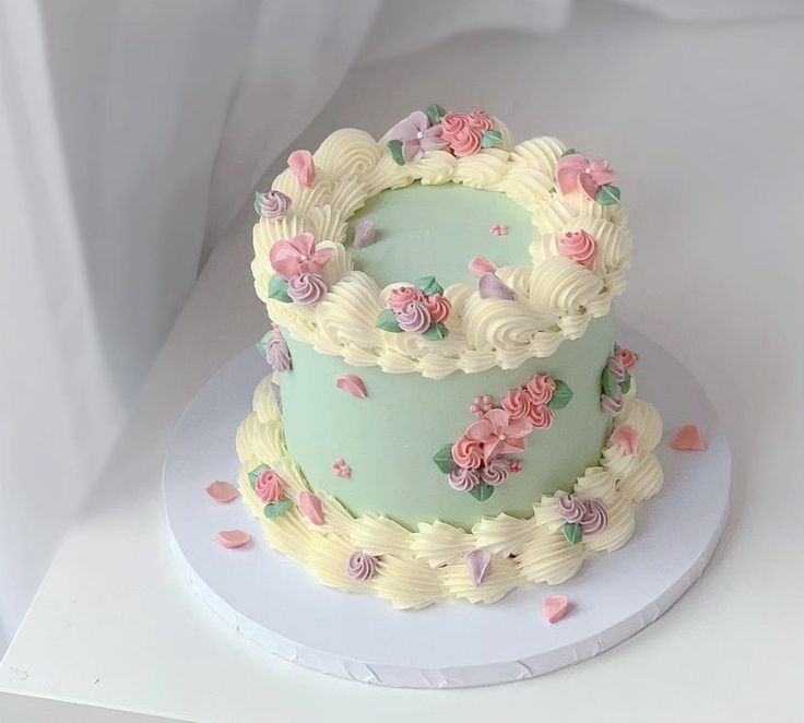 a three tiered cake decorated with flowers on a white tablecloth covered surface, ready to be eaten