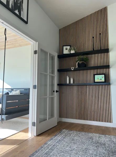 a living room with some shelves on the wall and a rug in front of it