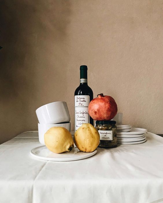 there is a plate with some food on it next to a bottle of wine and plates