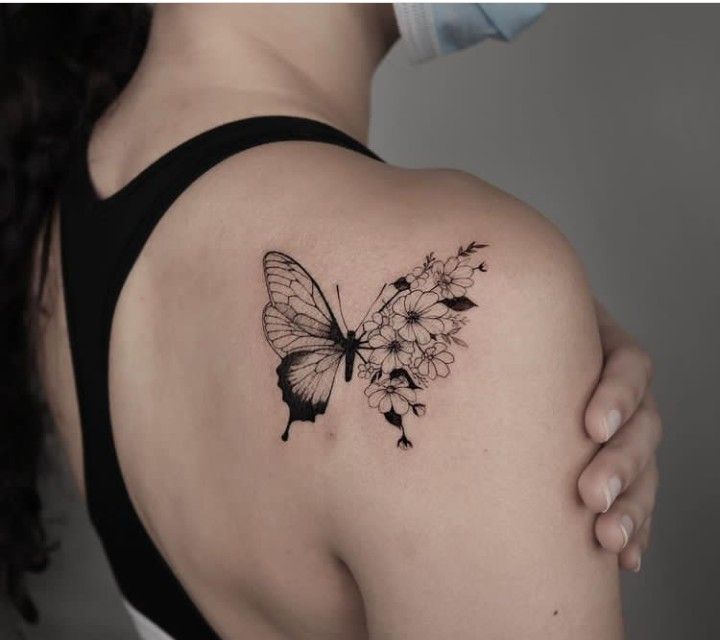 a woman's back shoulder with a butterfly and flowers tattoo on her left arm