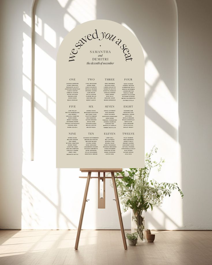 a table plan sitting on top of a easel next to a potted plant