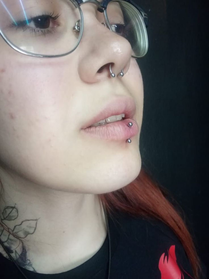 a woman with glasses and piercings on her nose