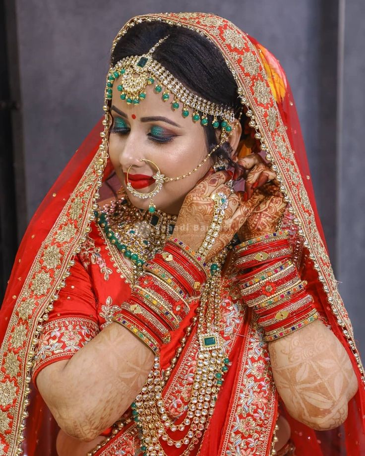 a woman dressed in red and gold is posing for the camera with her hands on her face