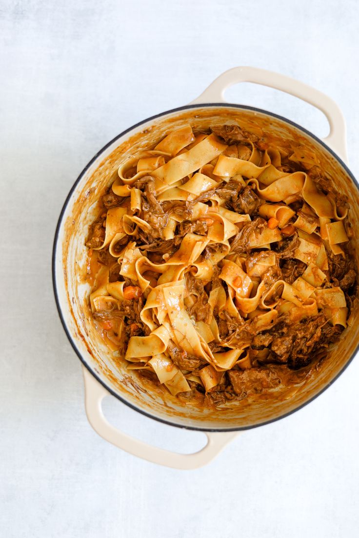 a pot filled with pasta and meat on top of a table