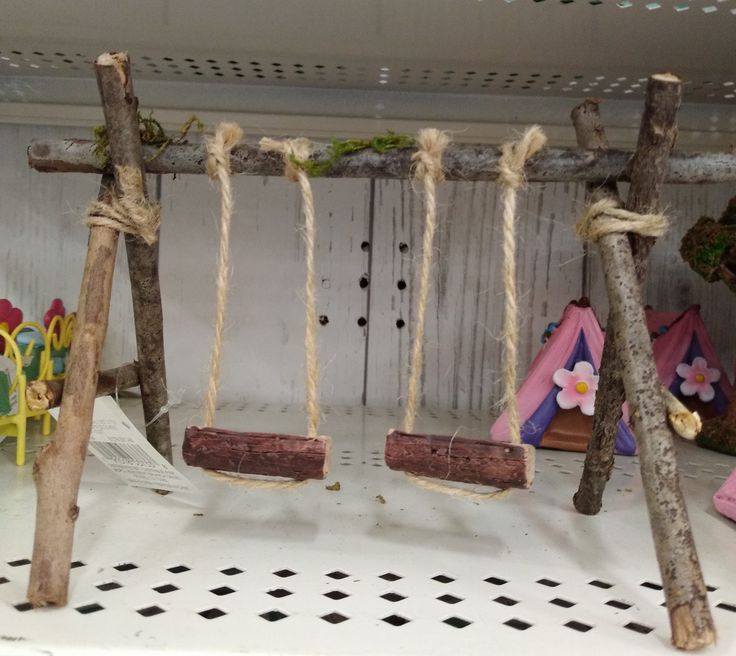 several swings made out of branches and rope with flowers on them in a playroom