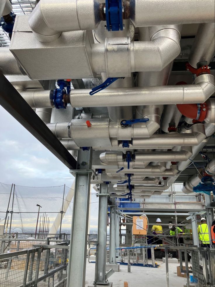 the pipes are connected to each other in an industrial area with construction workers standing around them