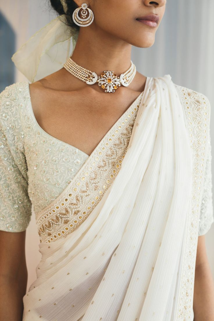 a woman wearing a white sari and jewelry