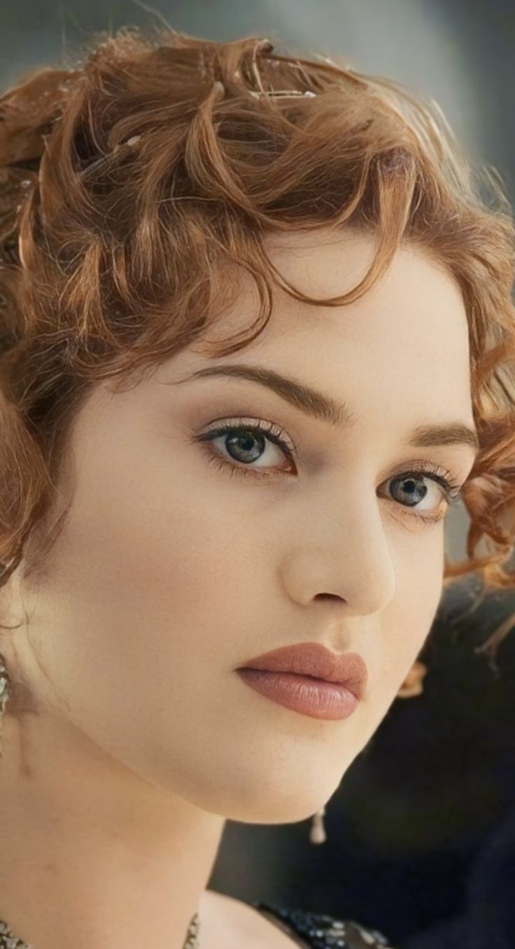 a close up of a woman with red hair and blue eyes wearing pearls on her head