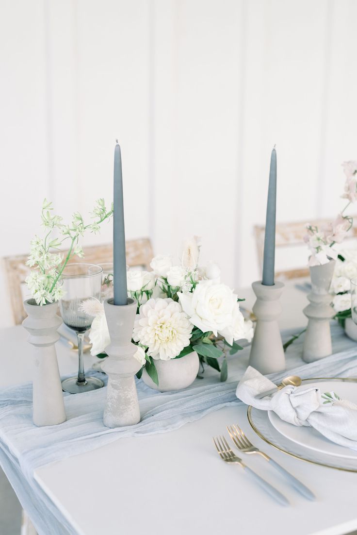 the table is set with white flowers and blue candlesticks for an elegant touch