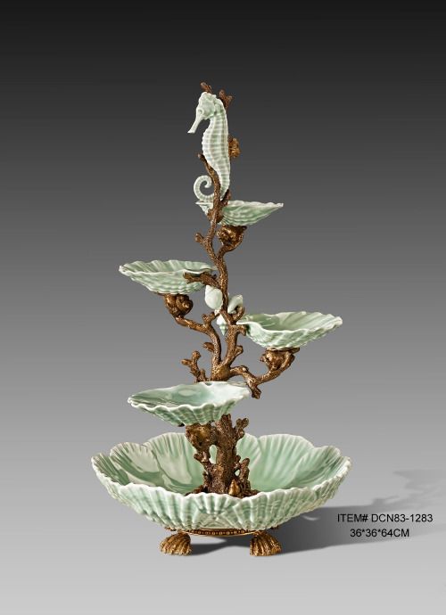 a green vase with two seahorses on it's sides and a bowl in the middle