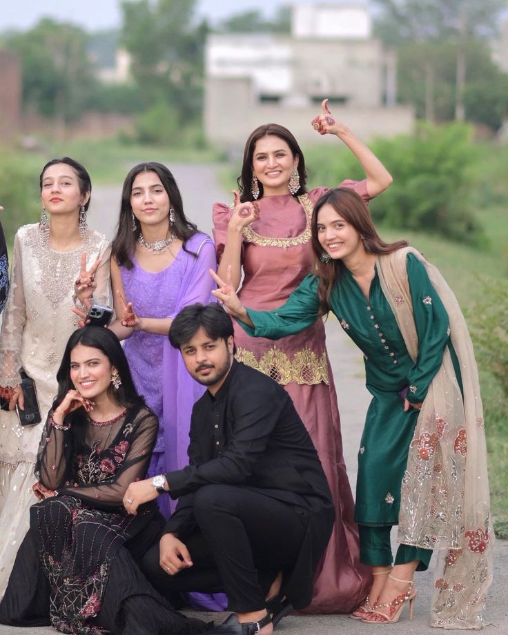 a group of people standing next to each other posing for a photo on the sidewalk